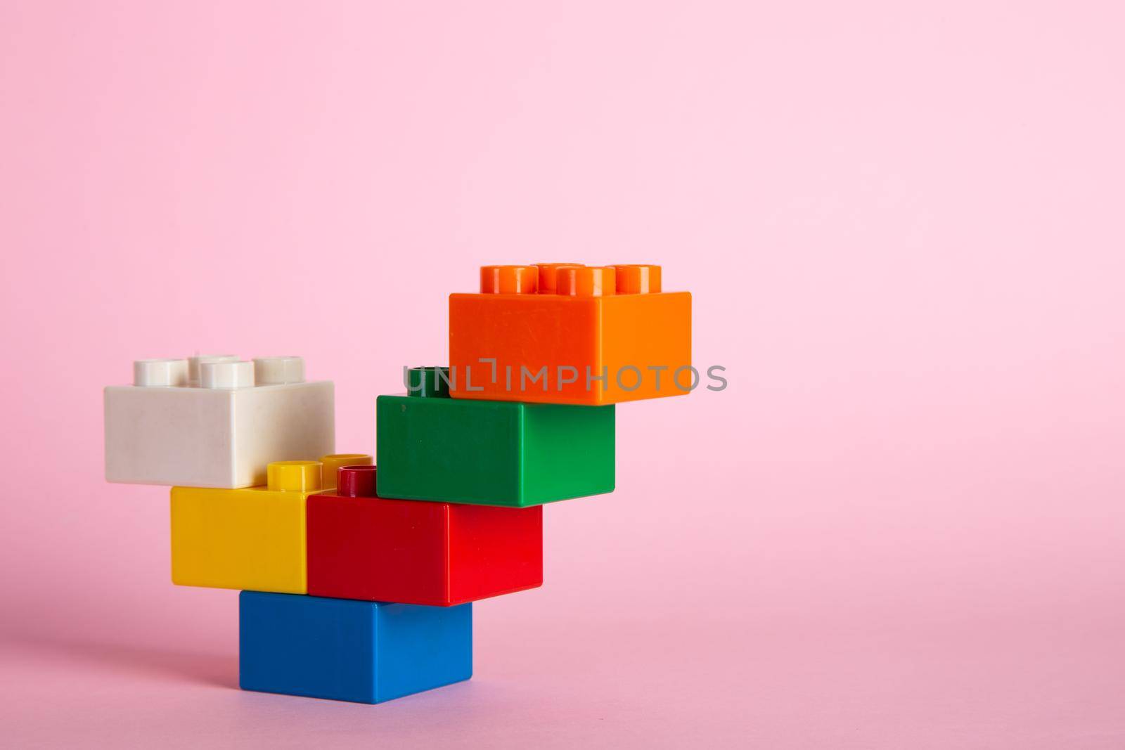 Plastic building blocks on pink background
