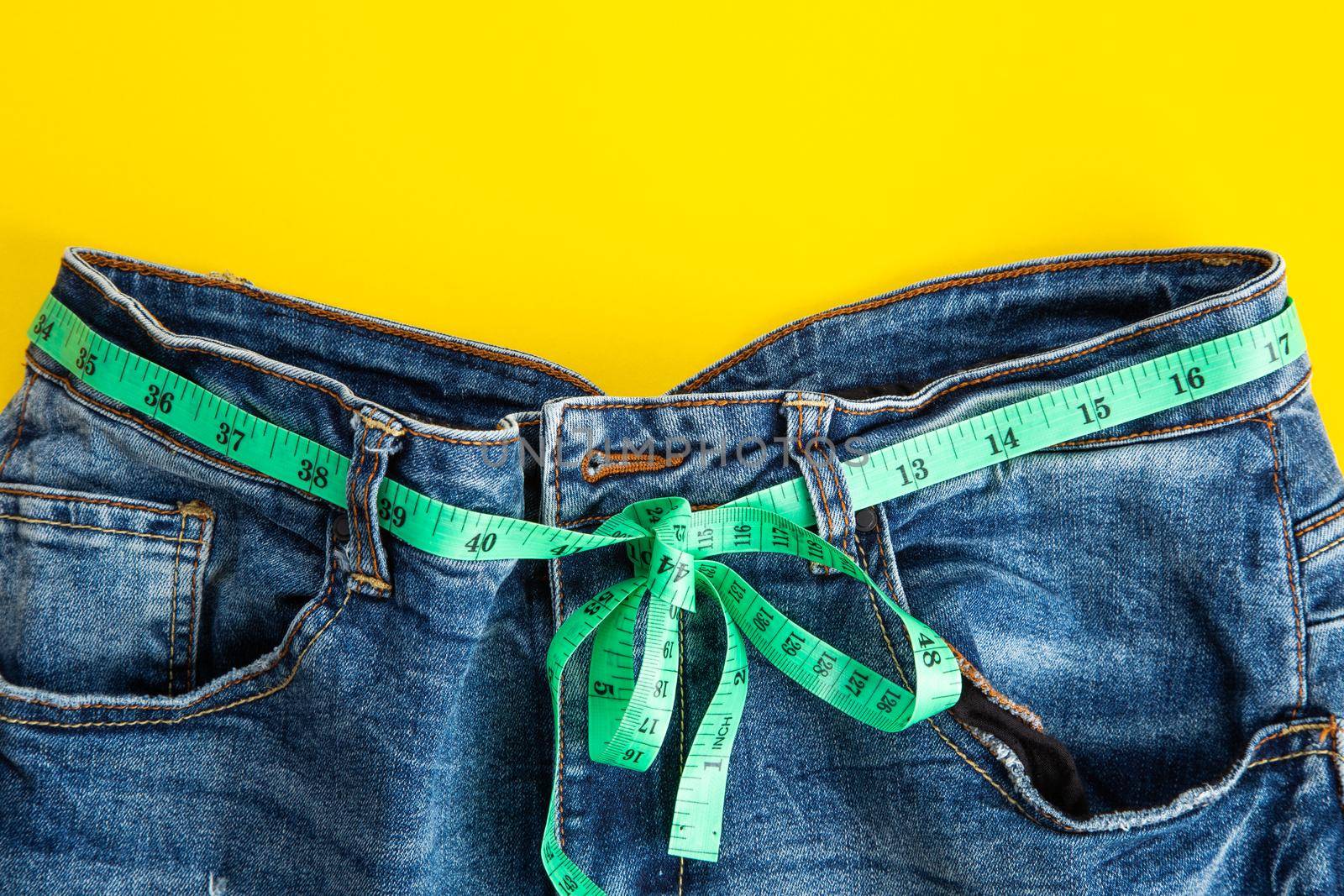 jeans with meter belt slimming on the yellow background. Diet ans slimming concept