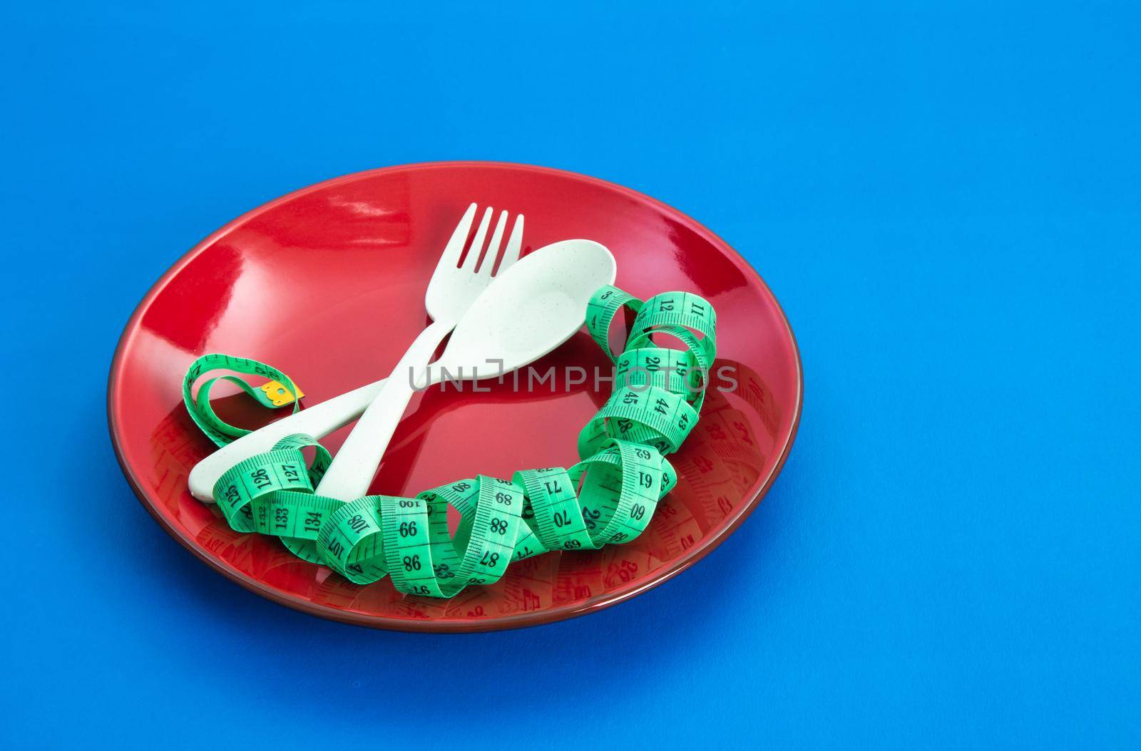 Diet for weight loss concept. Proper nutrition. Empty plate with fork and measuring tape.