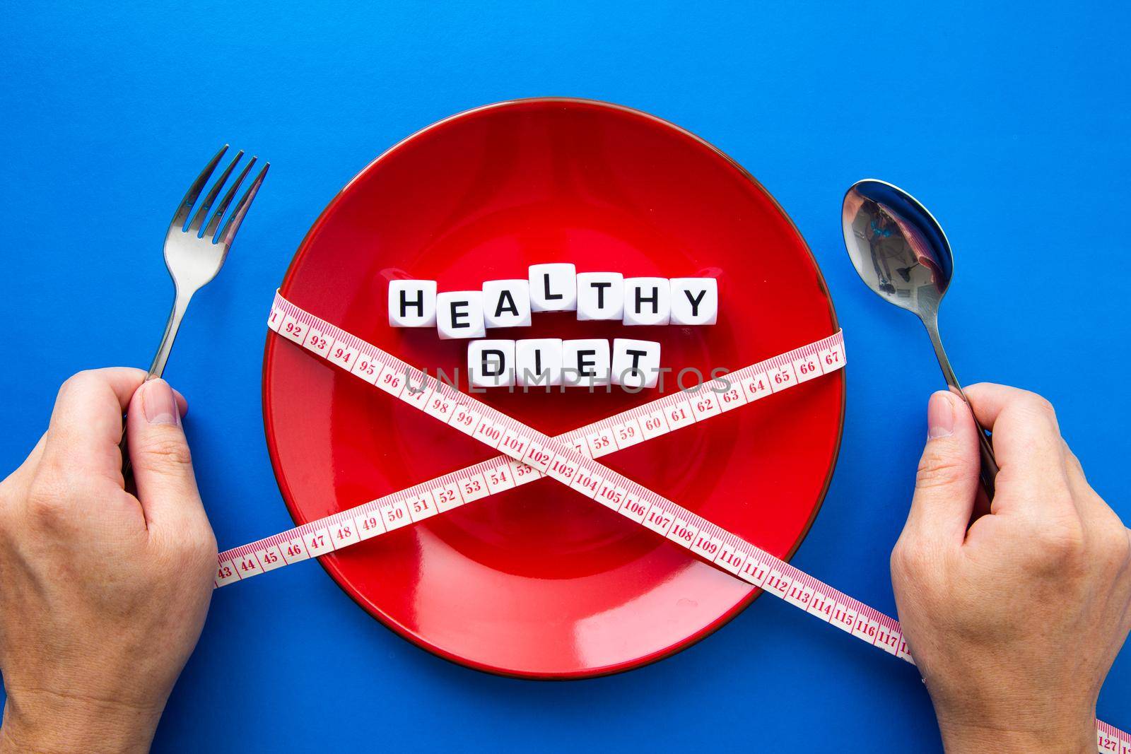 Weight loss and diet concept. Hands holding cutlery on wooden table.Plate with spoon, fork and measure tape