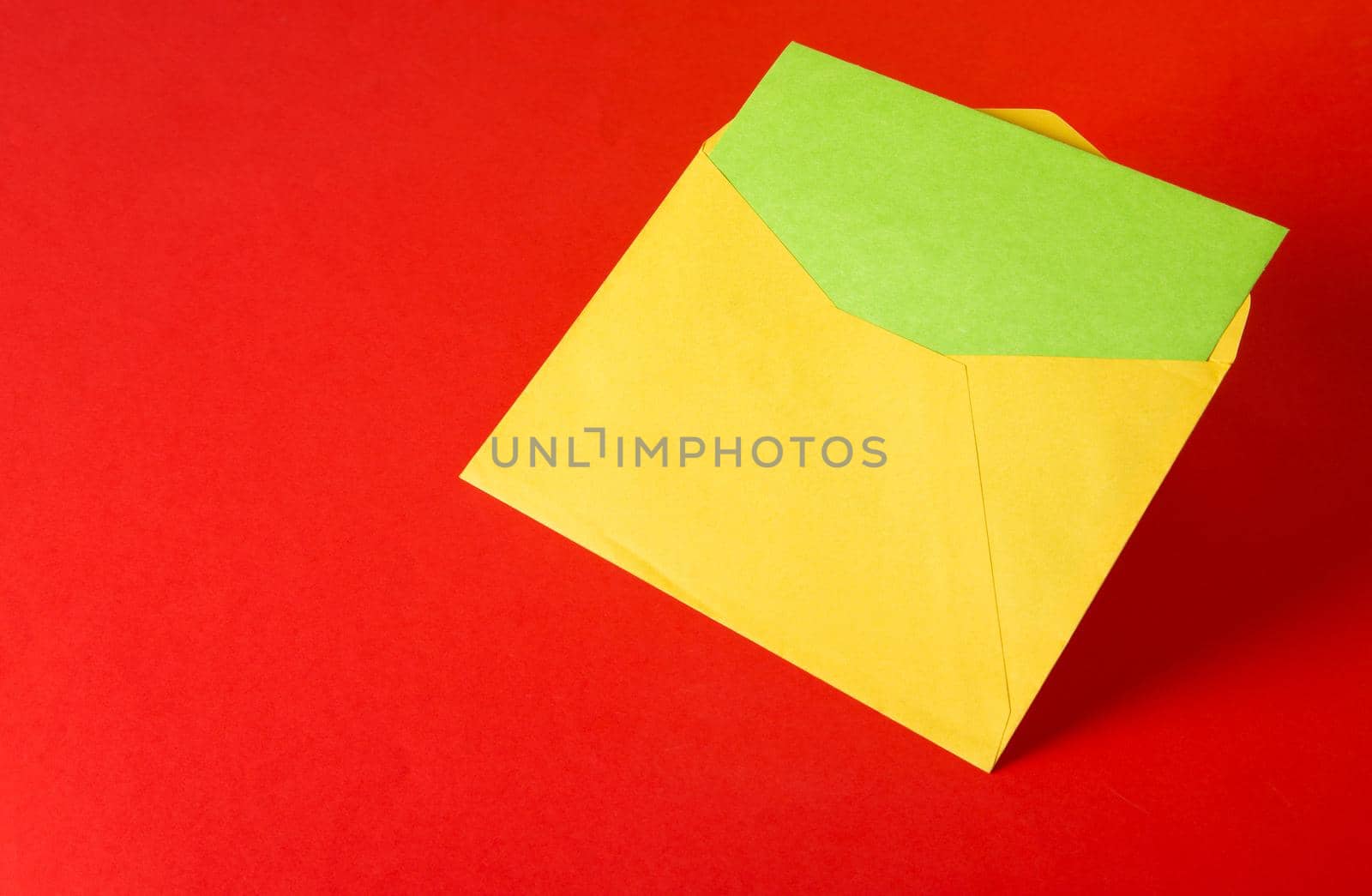 Colorful paper envelopes on red background - top view