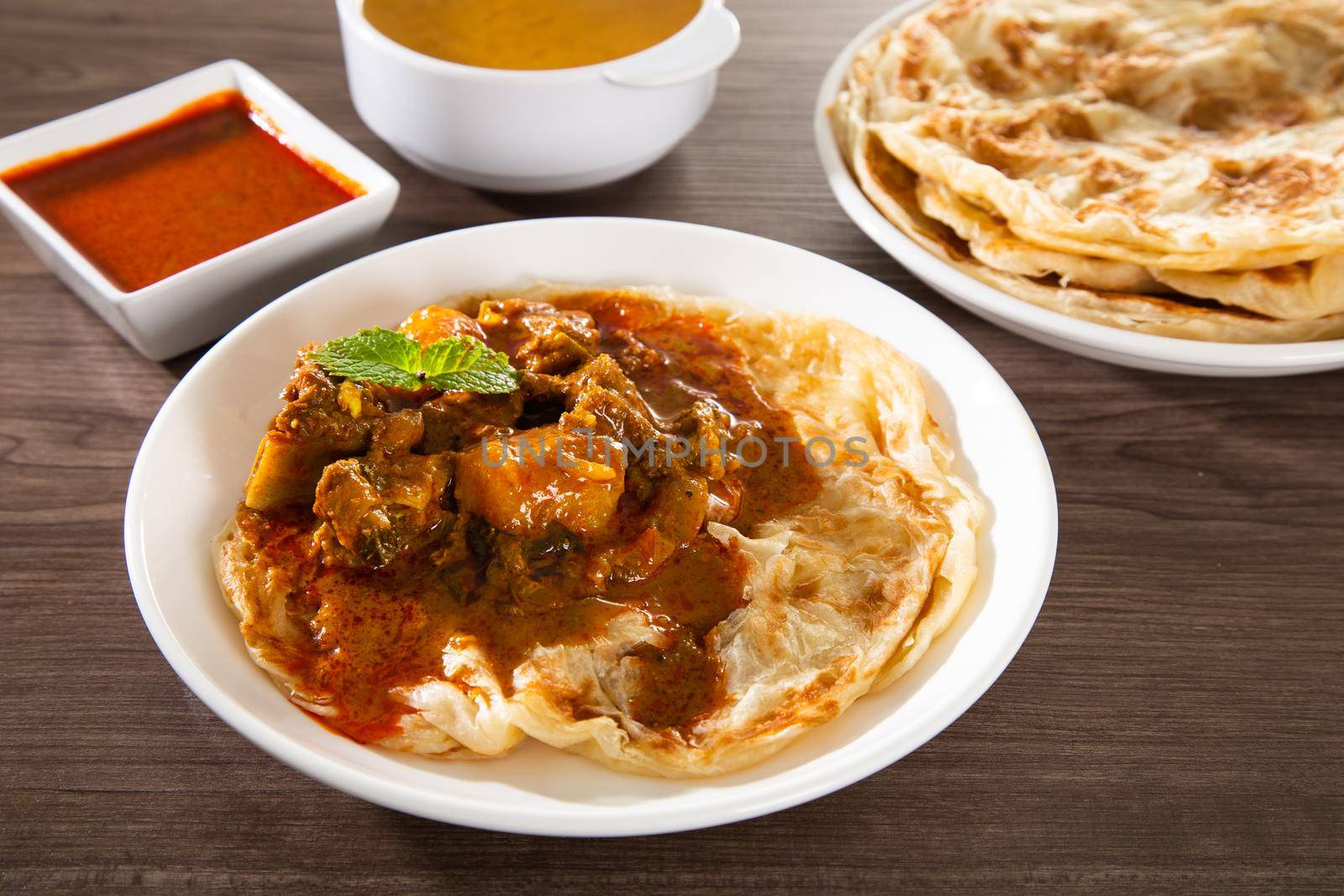 Roti Parata or Roti canai with lamb curry sauce - popular Malaysian breakfast