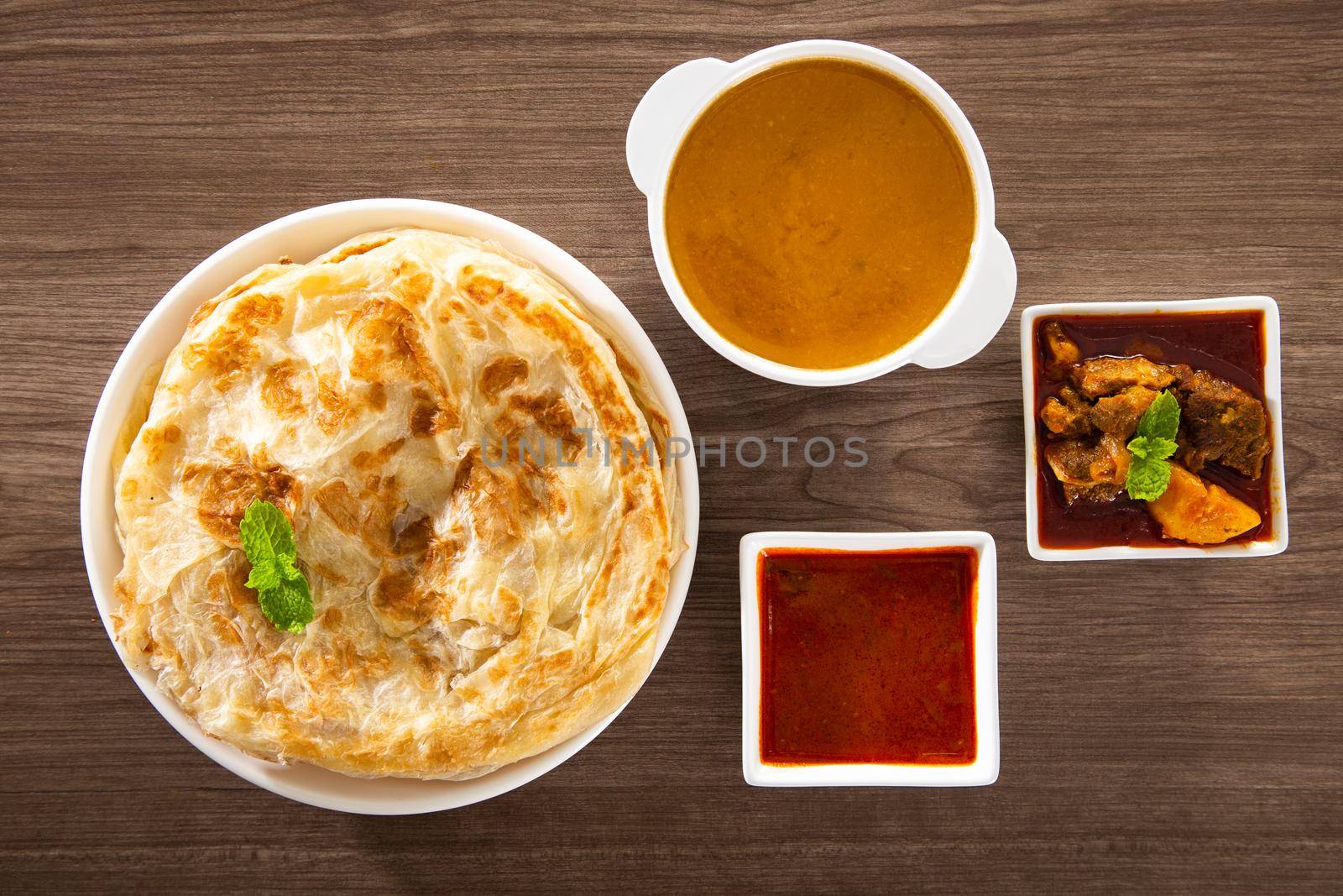 Roti Parata or Roti canai with lamb curry sauce - popular Malaysian breakfast