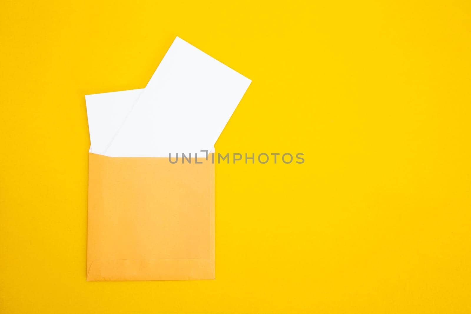 Colorful paper envelopes on yellow background - top view