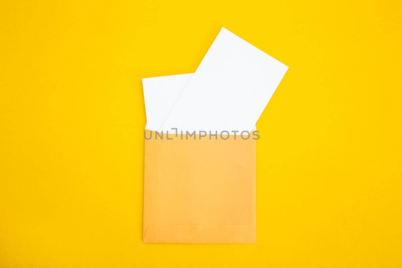 Colorful paper envelopes on yellow background - top view