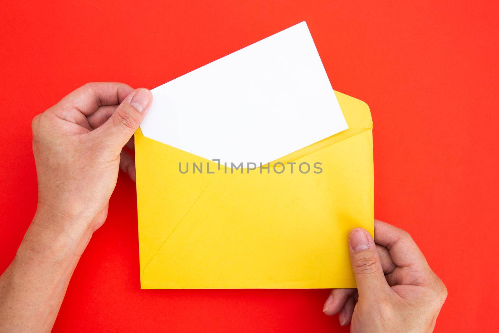 Hand holding a blank white card in color envelope