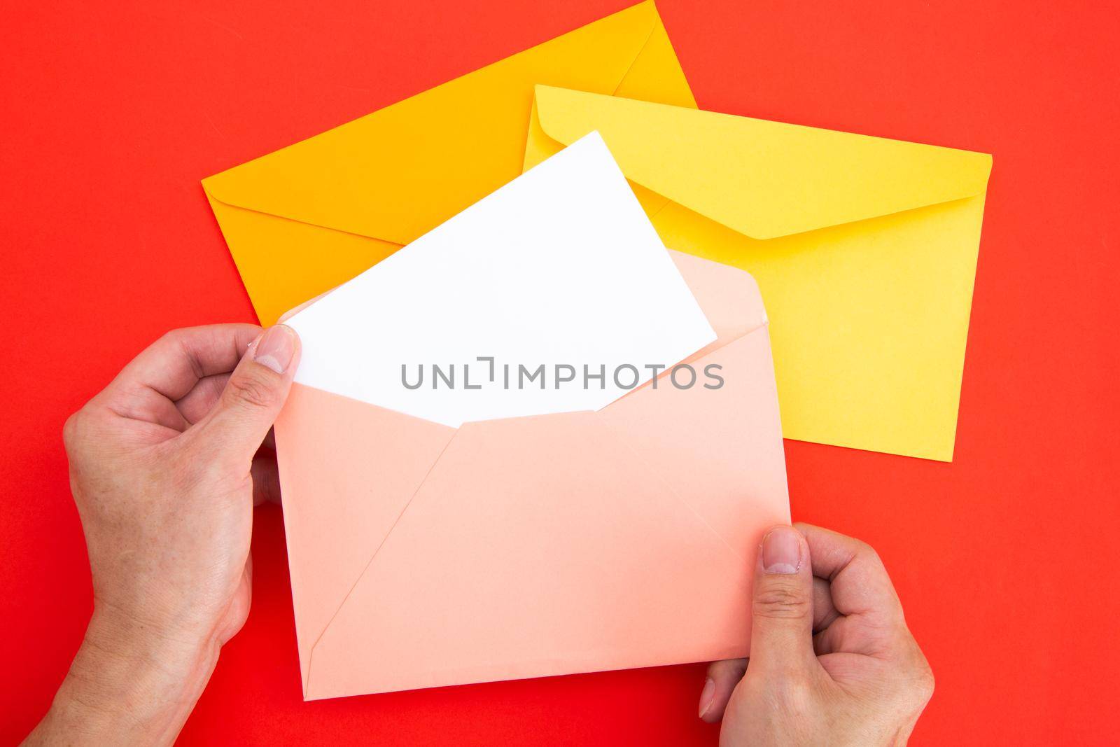 Hand holding a blank white card in color envelope
