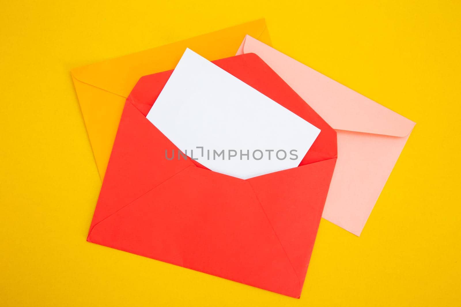 Colorful paper envelopes on yellow background - top view