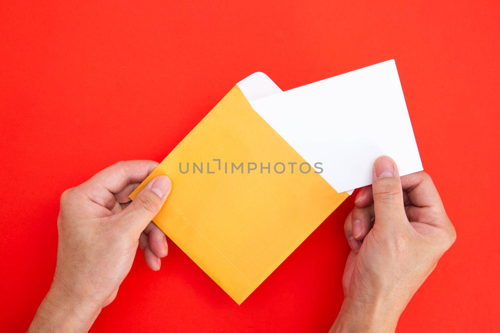 Hand holding a blank white card in color envelope
