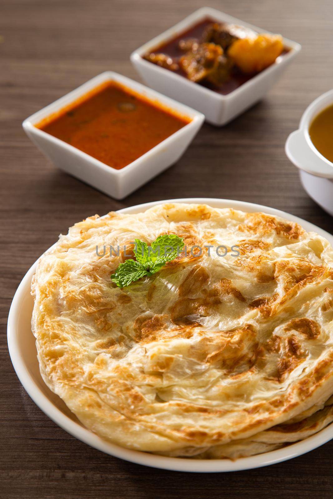 Roti Parata or Roti canai with lamb curry sauce - popular Malaysian breakfast