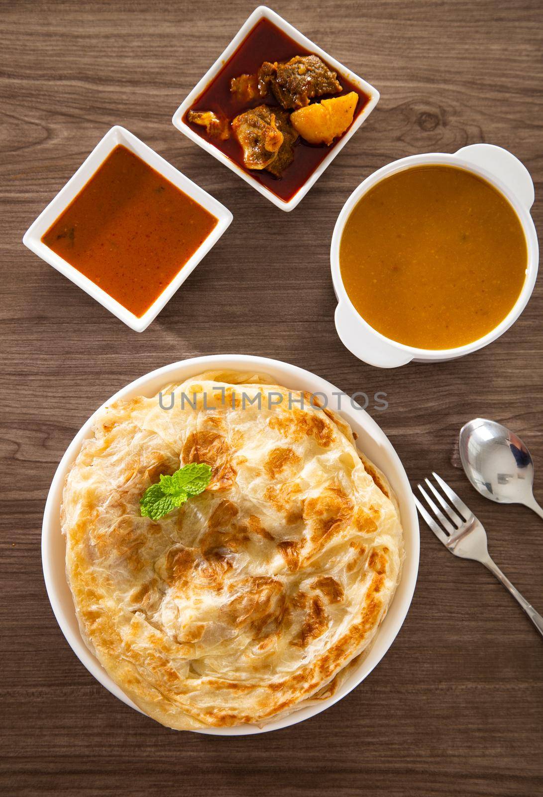 Roti Parata or Roti canai with lamb curry sauce - popular Malaysian breakfast