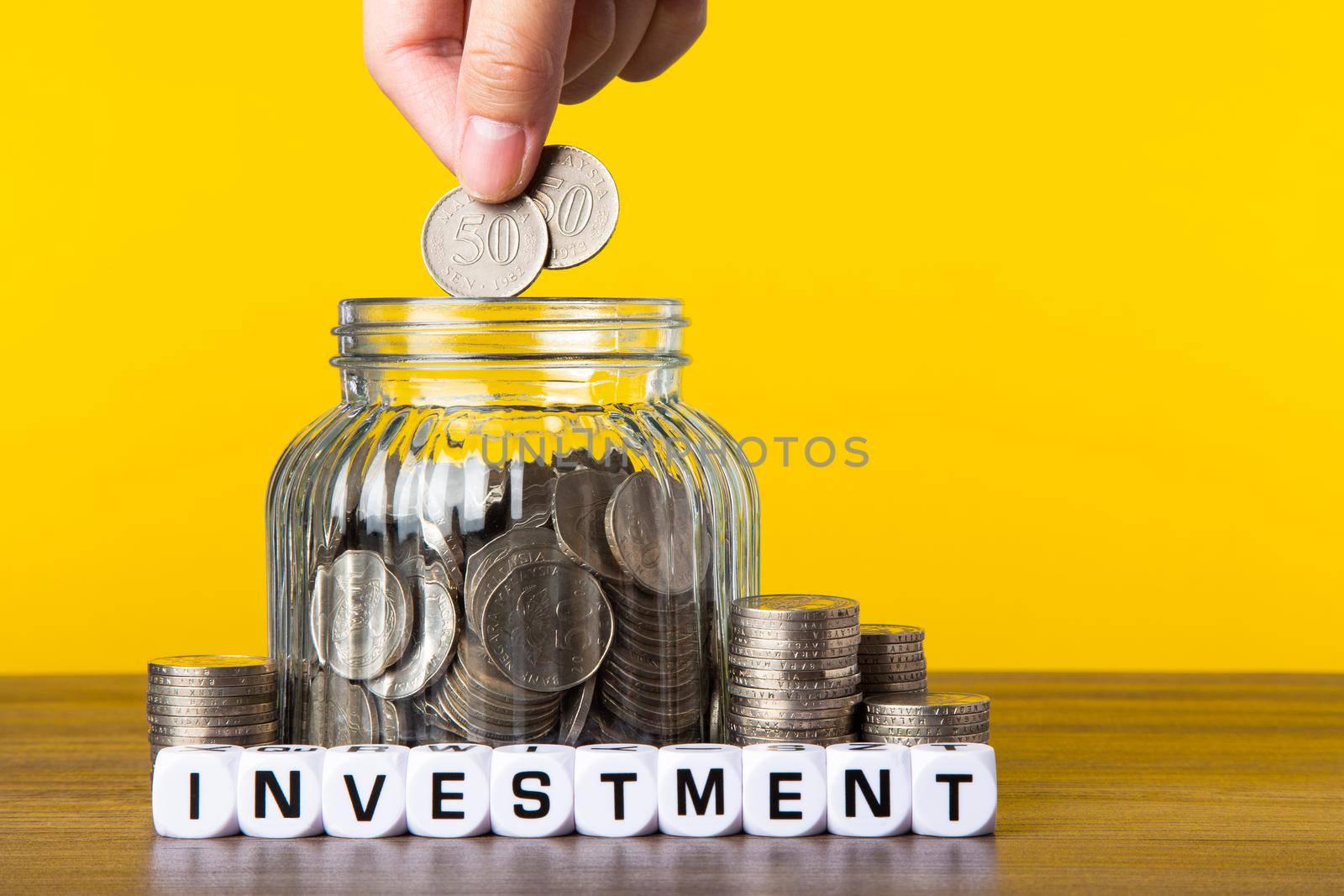 A lot coins in glass money jar with yellow background. Saving for Investment concept.