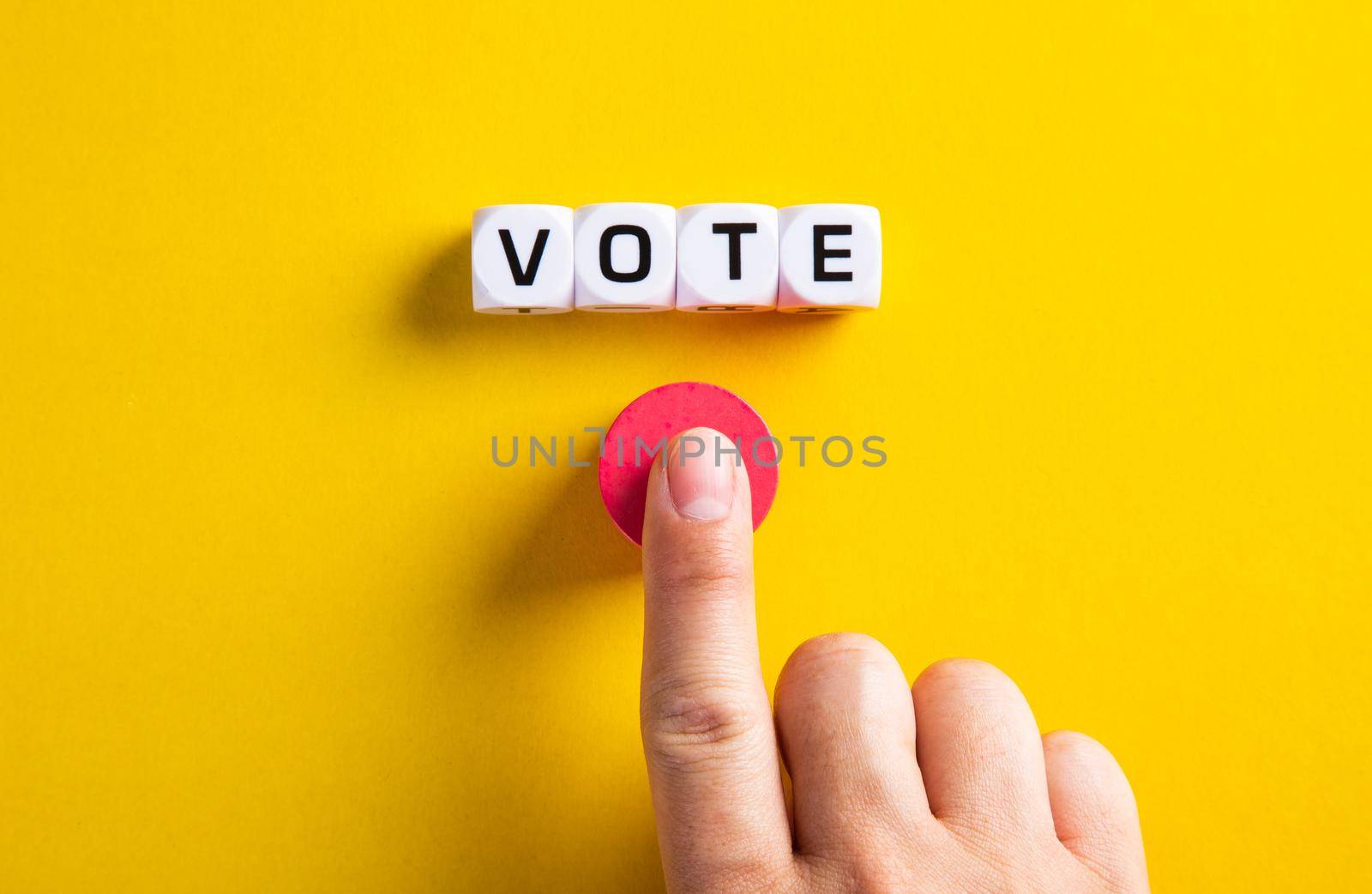 Hand with word vote on yellow background. Voting in political election or in business concept.