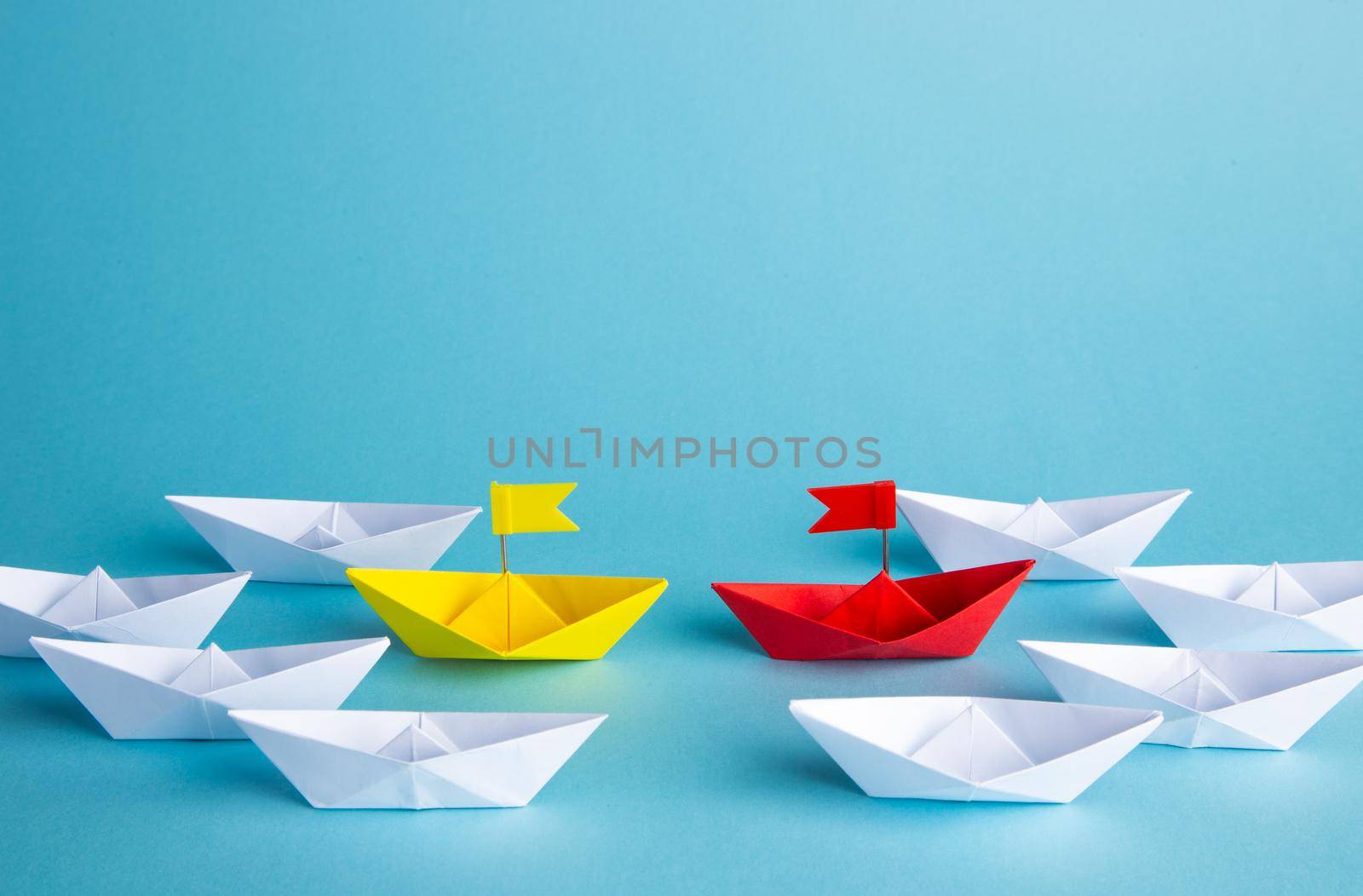 Leadership concept. Red leader paper ship leading among others on blue background.