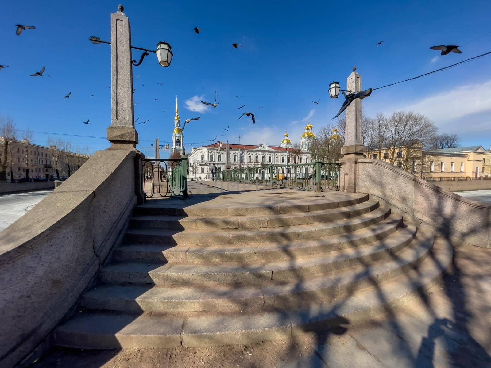 Russia, St. Petersburg, 01 April 2021: St. Nicholas Naval Cathedral belltower in a clear sunny day of spring, an ice drift on Kryukov and Griboyedov Canal, a view of seven bridges from the embankment by vladimirdrozdin