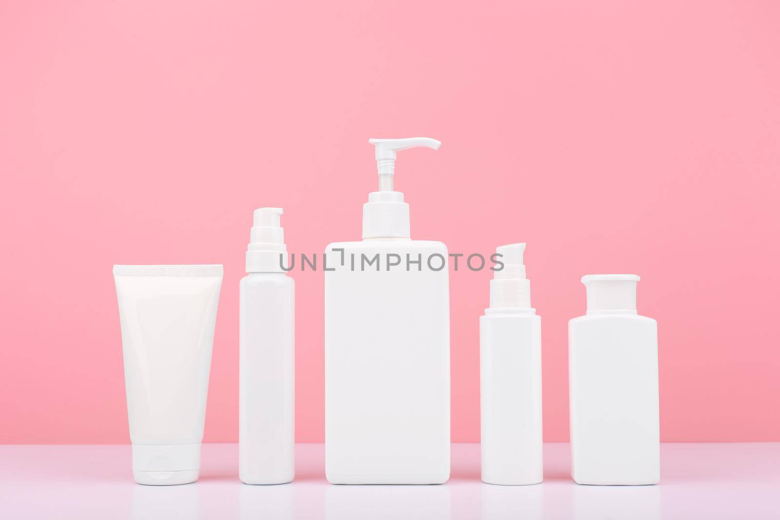 Set of cosmetic products for skin and body care on white table against bright pink background. Concept of health care and beauty