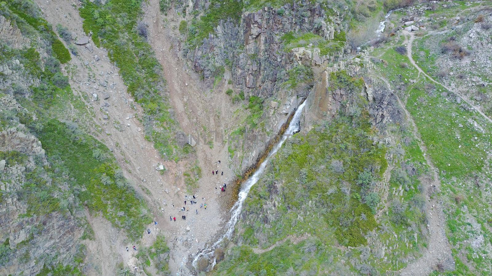 Top view of the waterfall among the rocks. Highest waterfall, and longest river. Grass and trees grow on the rock. A group of people can be seen below. Outdoor recreation. Mountainous area.