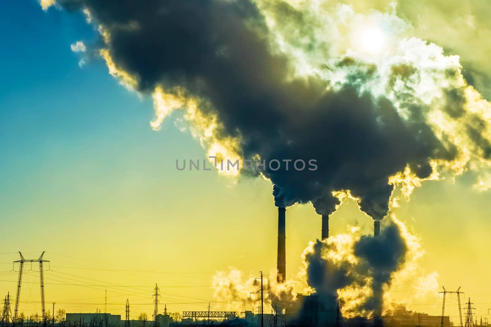 Sunset over the industrial city.Factory chimneys smoke.Environmental problem of environmental and atmospheric pollution.Climate change,environmental disaster.The sky is smoky with toxic substances by YevgeniySam