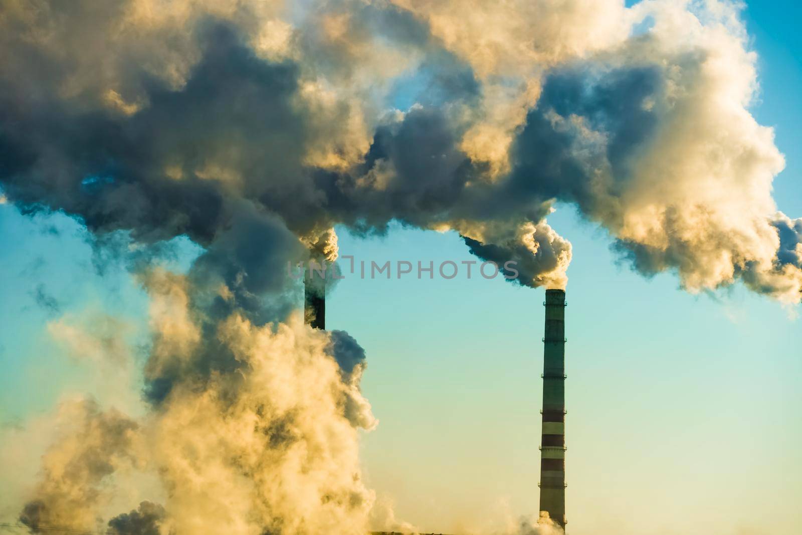 Sunset over the industrial city.Factory chimneys smoke.Environmental problem of environmental and atmospheric pollution.Climate change,environmental disaster.The sky is smoky with toxic substances by YevgeniySam