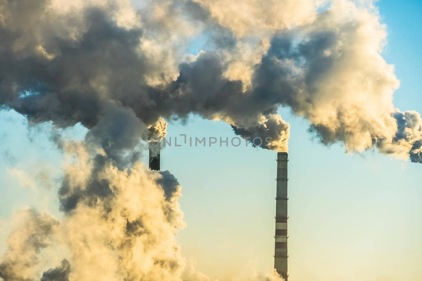 Sunset over the industrial city.Factory chimneys smoke.Environmental problem of environmental and atmospheric pollution.Climate change,environmental disaster.The sky is smoky with toxic substances by YevgeniySam