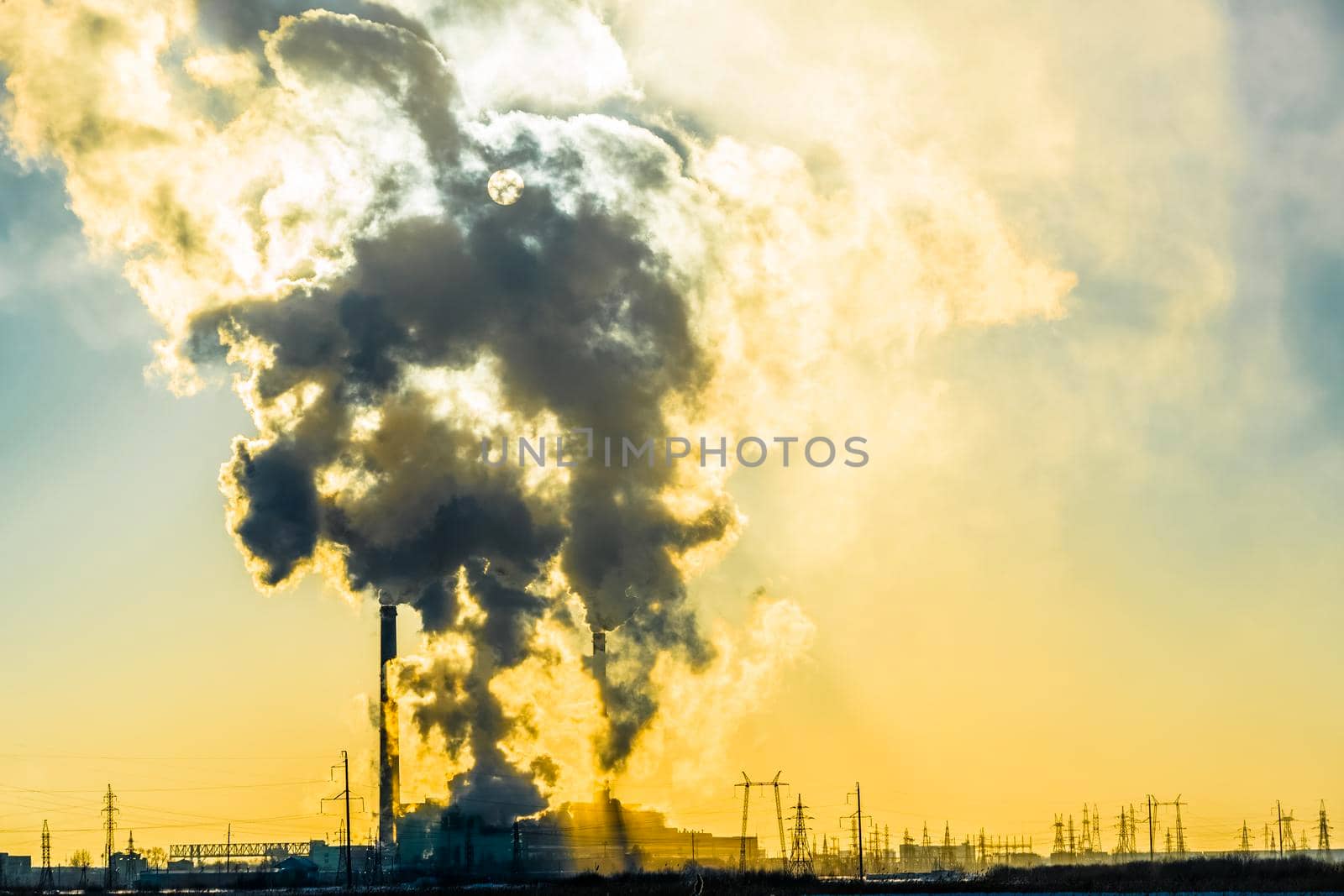 Sunset over the industrial city.Factory chimneys smoke.Environmental problem of environmental and atmospheric pollution.Climate change,environmental disaster.The sky is smoky with toxic substances by YevgeniySam