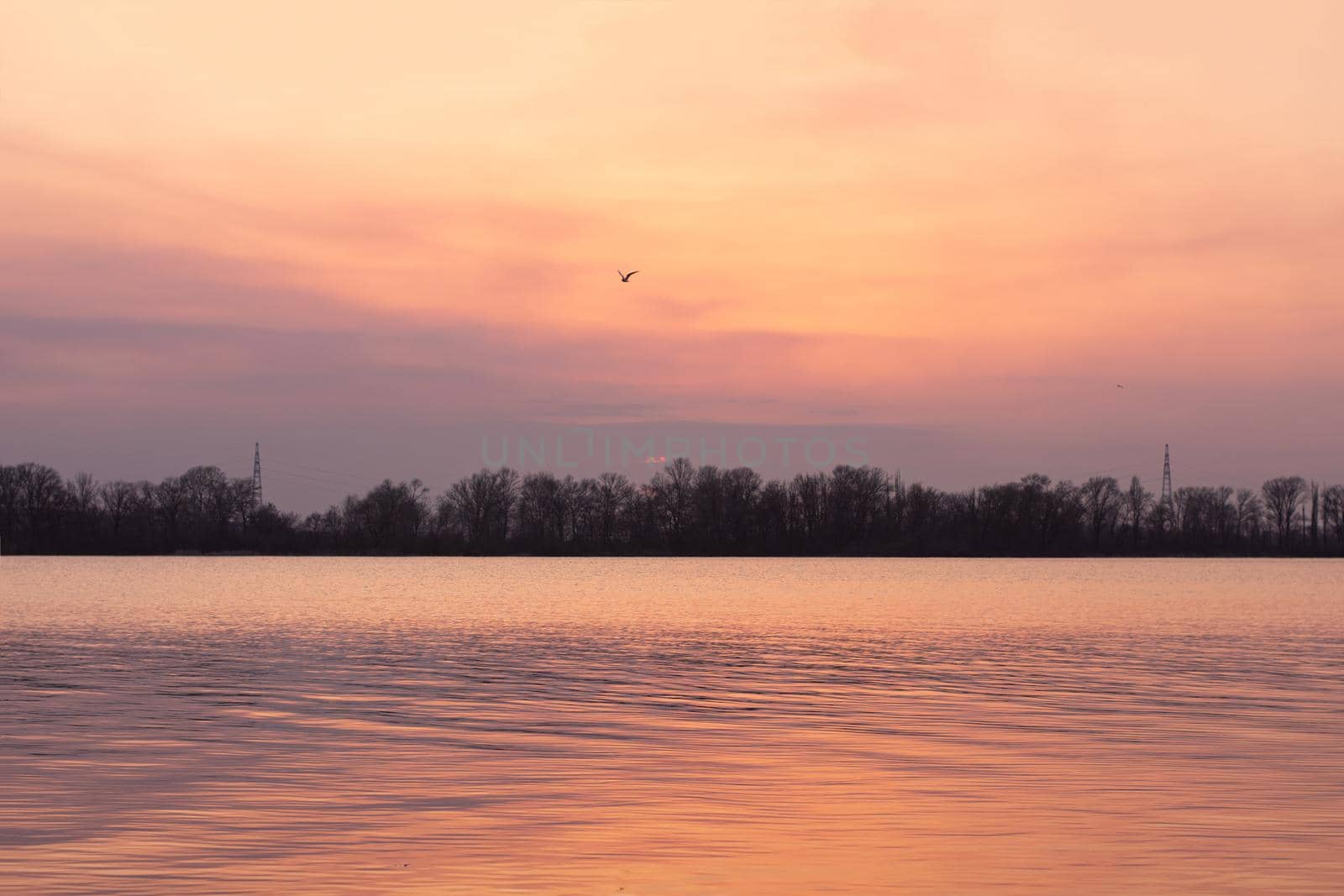 Sunset on the river. The sun sank below the horizon. Spring landscape. Ripples on the water. Dnipro, Ukraine.