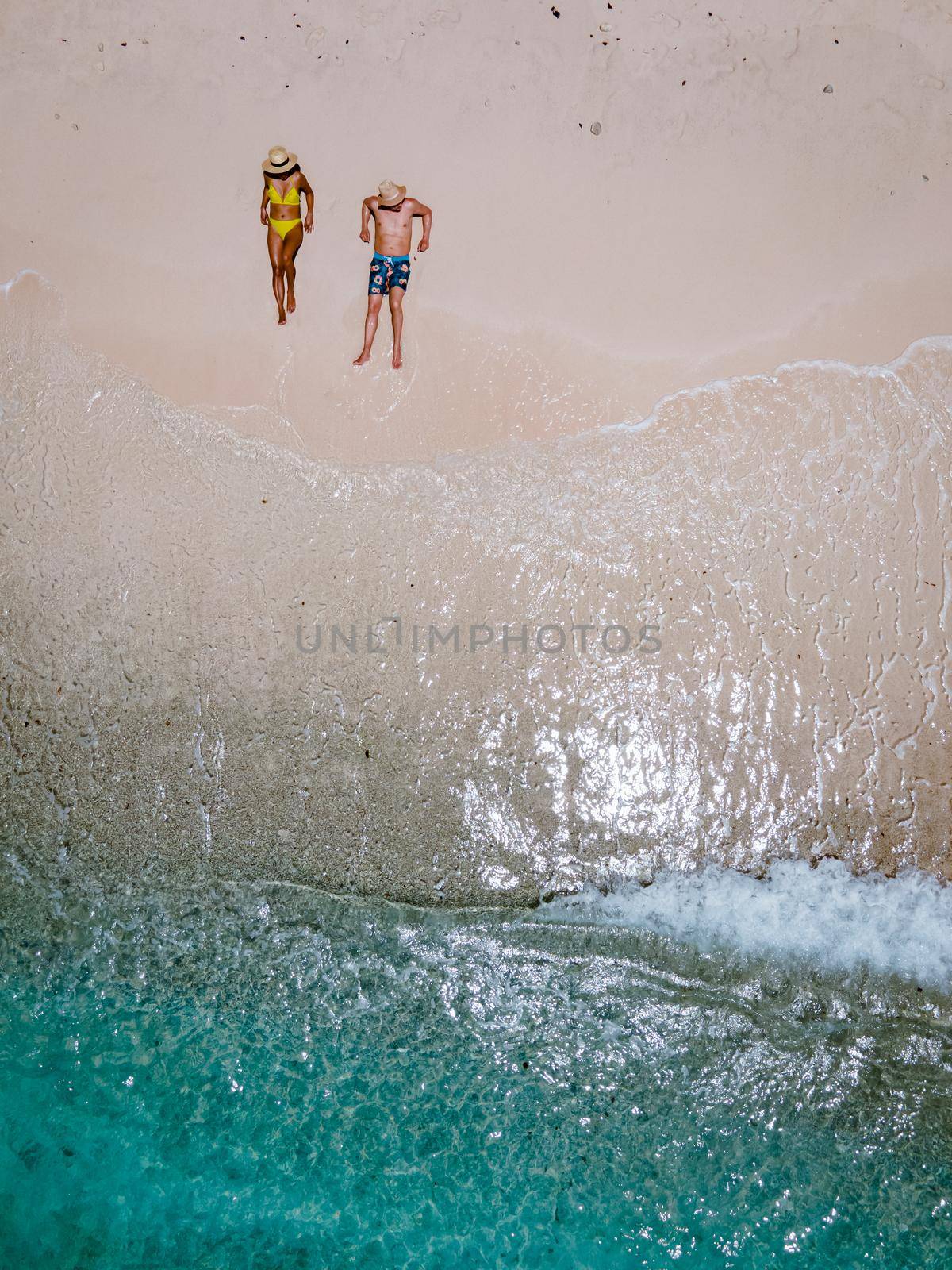 Playa Kalki Curacao tropical Island in the Caribbean sea, Playa Kalki western side of Curacao Caribbean Dutch Antilles azure ocean, drone aerial view of couple men and woman on the beach from above