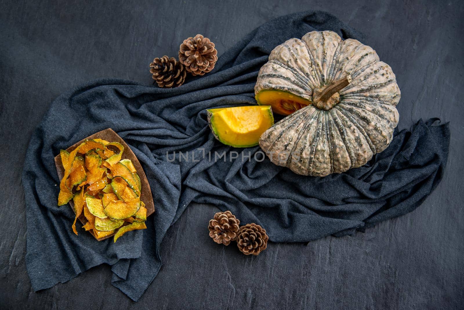 Flat Lay composition with delicious of Homemade crispy pumpkin chips on Black stone texture. Oblique view from the top.
