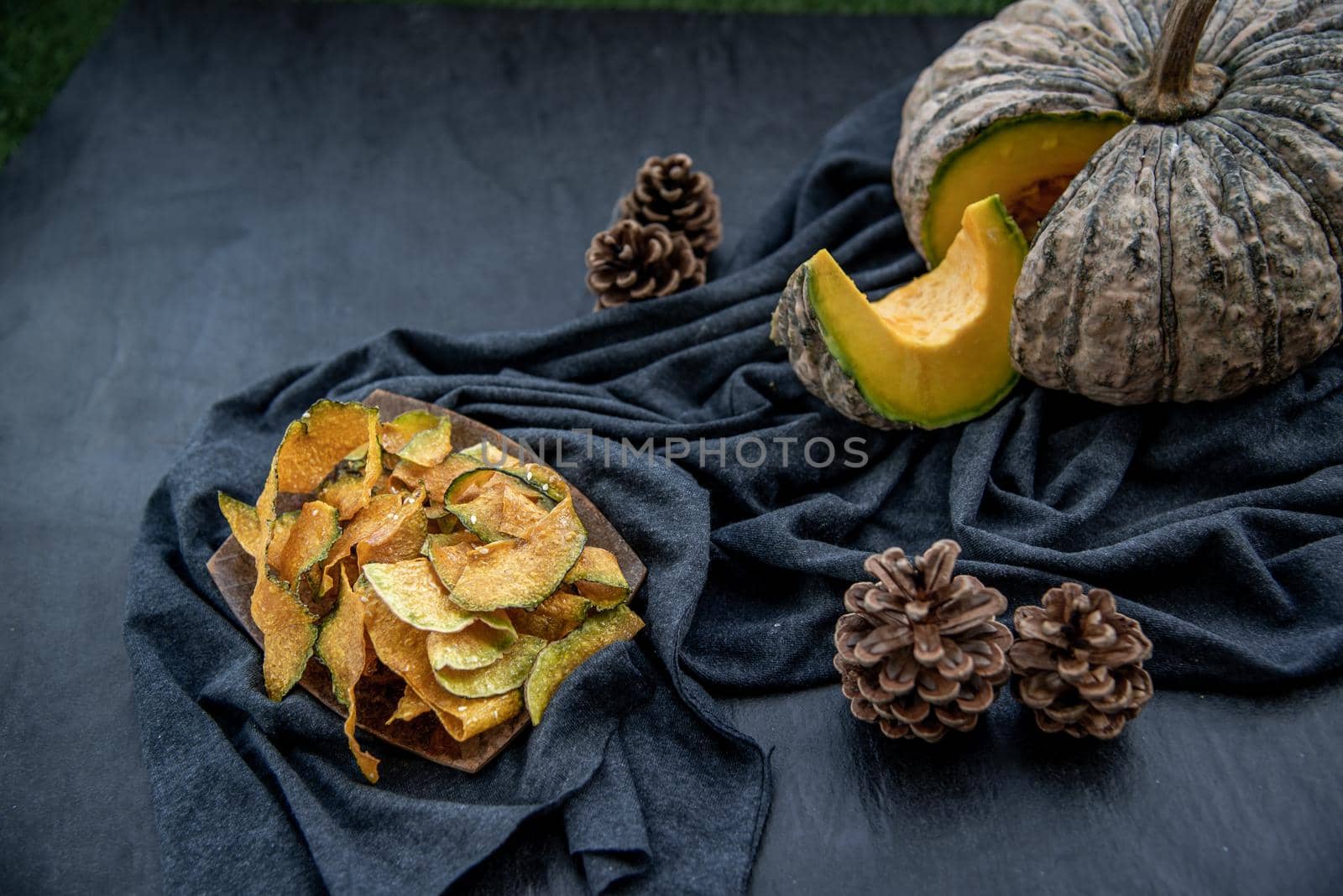 Flat Lay composition with delicious of Homemade crispy pumpkin chips on Black stone texture. Oblique view from the top.