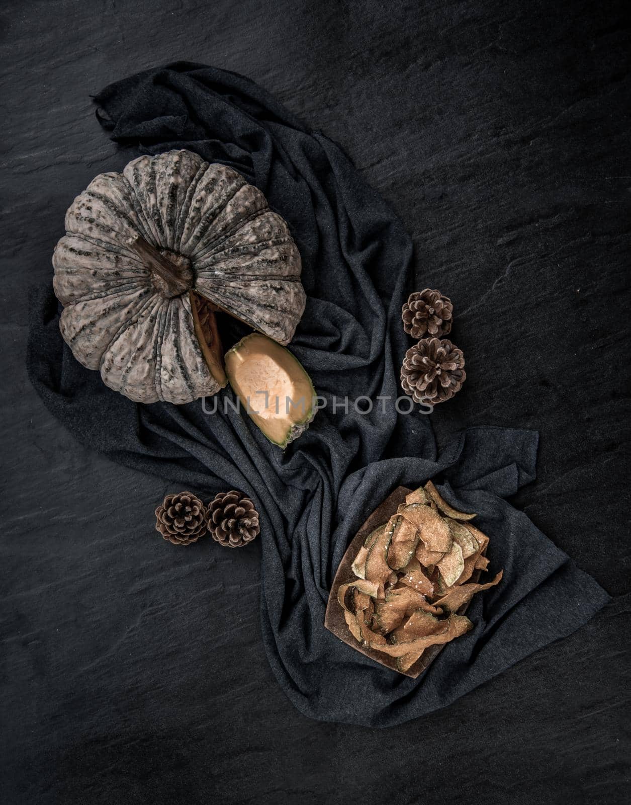 Flat Lay composition with delicious of Homemade crispy pumpkin chips on Black stone texture. Top view.