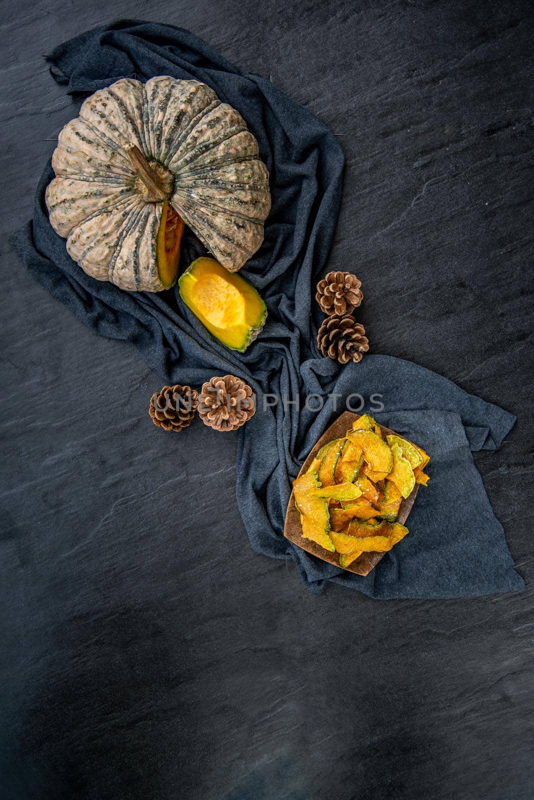 Flat Lay composition with delicious of Homemade crispy pumpkin chips on Black stone texture. Top view.