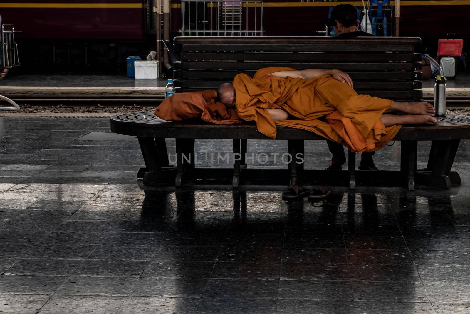 Bangkok, thailand - Jul 7, 2019 : A monk is sleep on wooden chairs are waiting for trains in the area provided at Main railway station of Hua Lamphong, Selective focus.