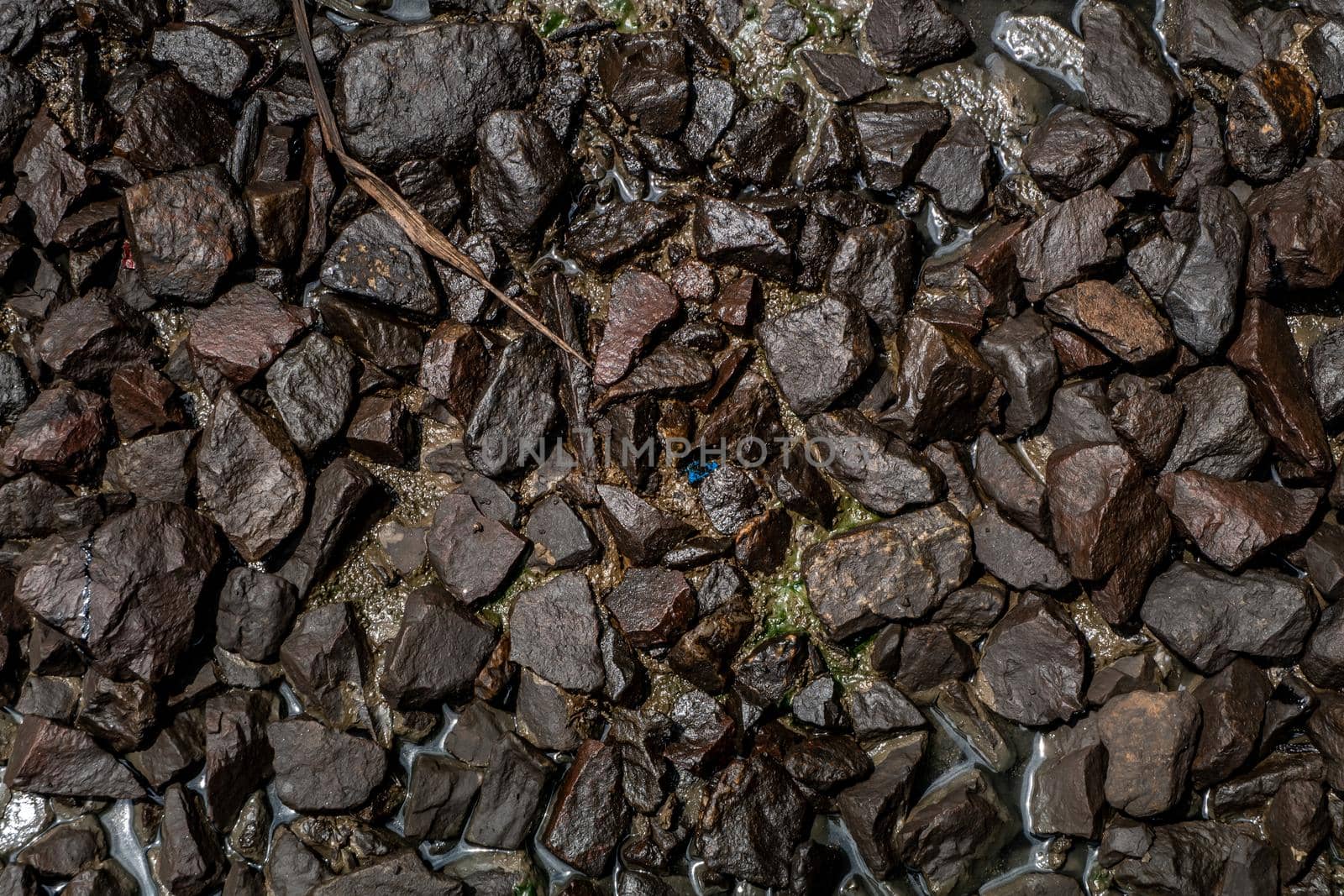 Ballast stone gravel soaked with engine oil in the railroad tracks, Stone background.