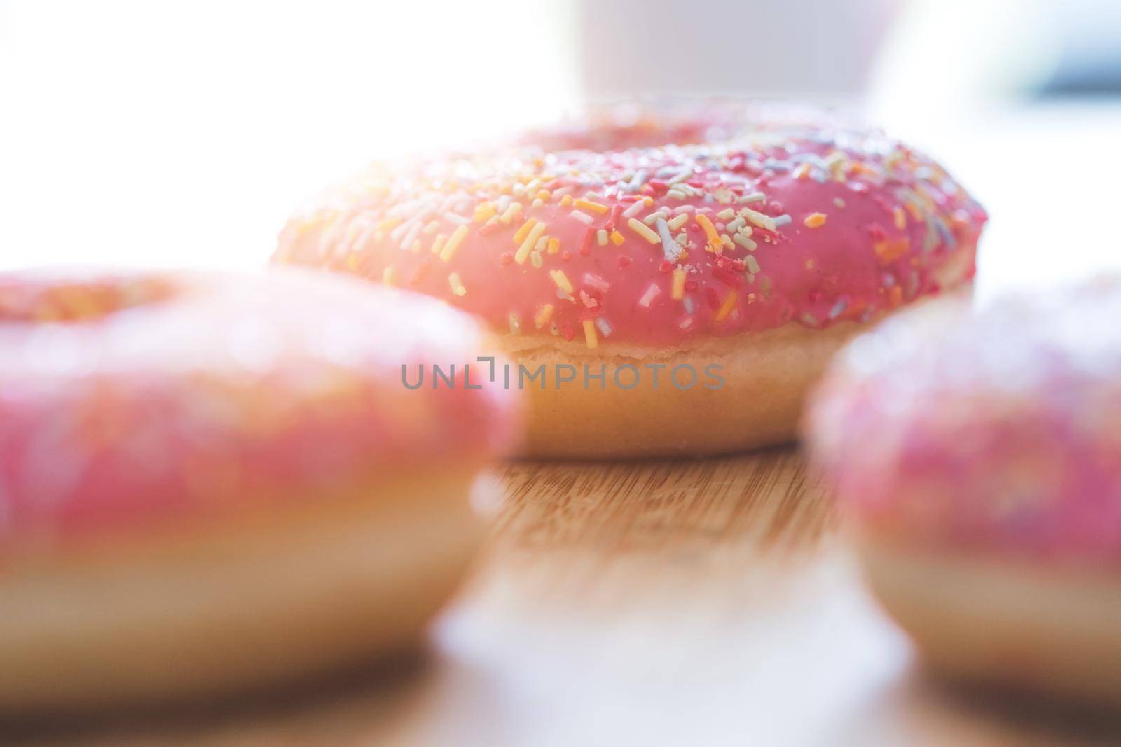 Sugar sprinkled pink donut on wooden plate