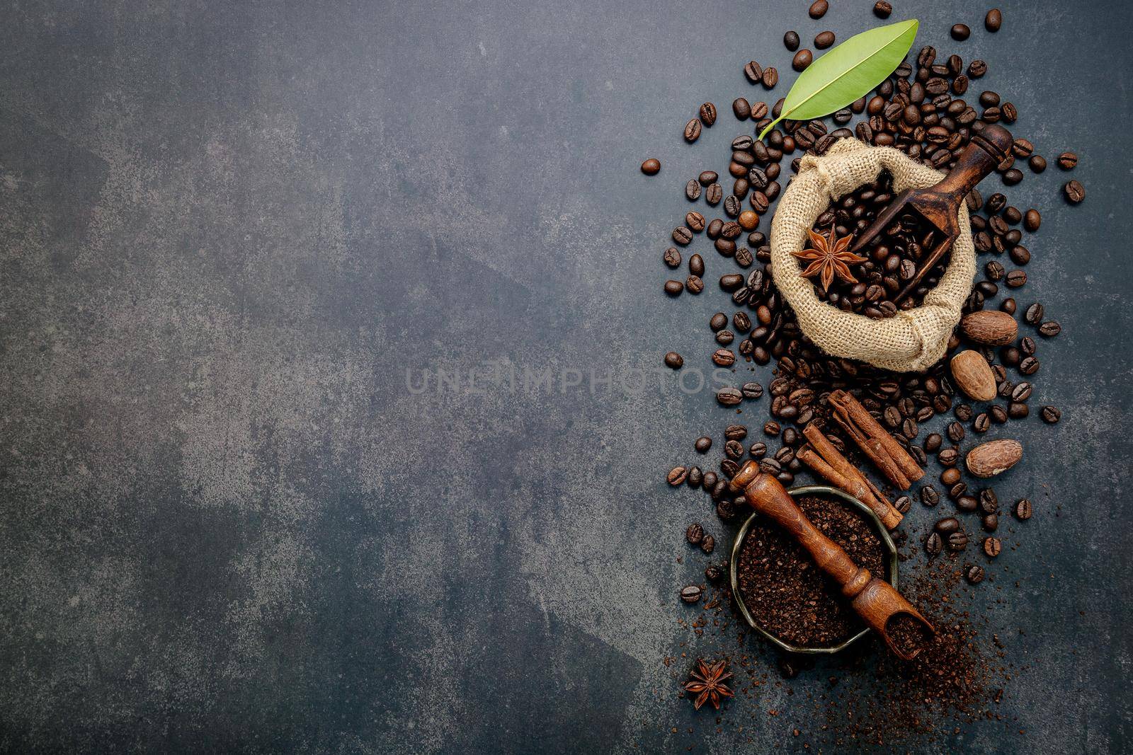  Roasted coffee beans with coffee powder and flavourful ingredients for make tasty coffee setup on dark stone background. by kerdkanno