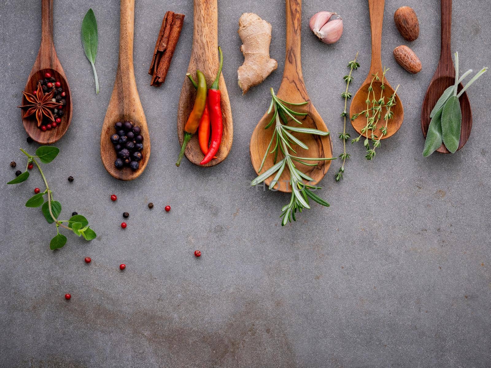Various of spices and herbs in wooden spoons. Flat lay spices ingredients chili ,peppercorn, rosemarry, thyme,star anise ,sage leaves and sweet basil on concrete background. by kerdkanno