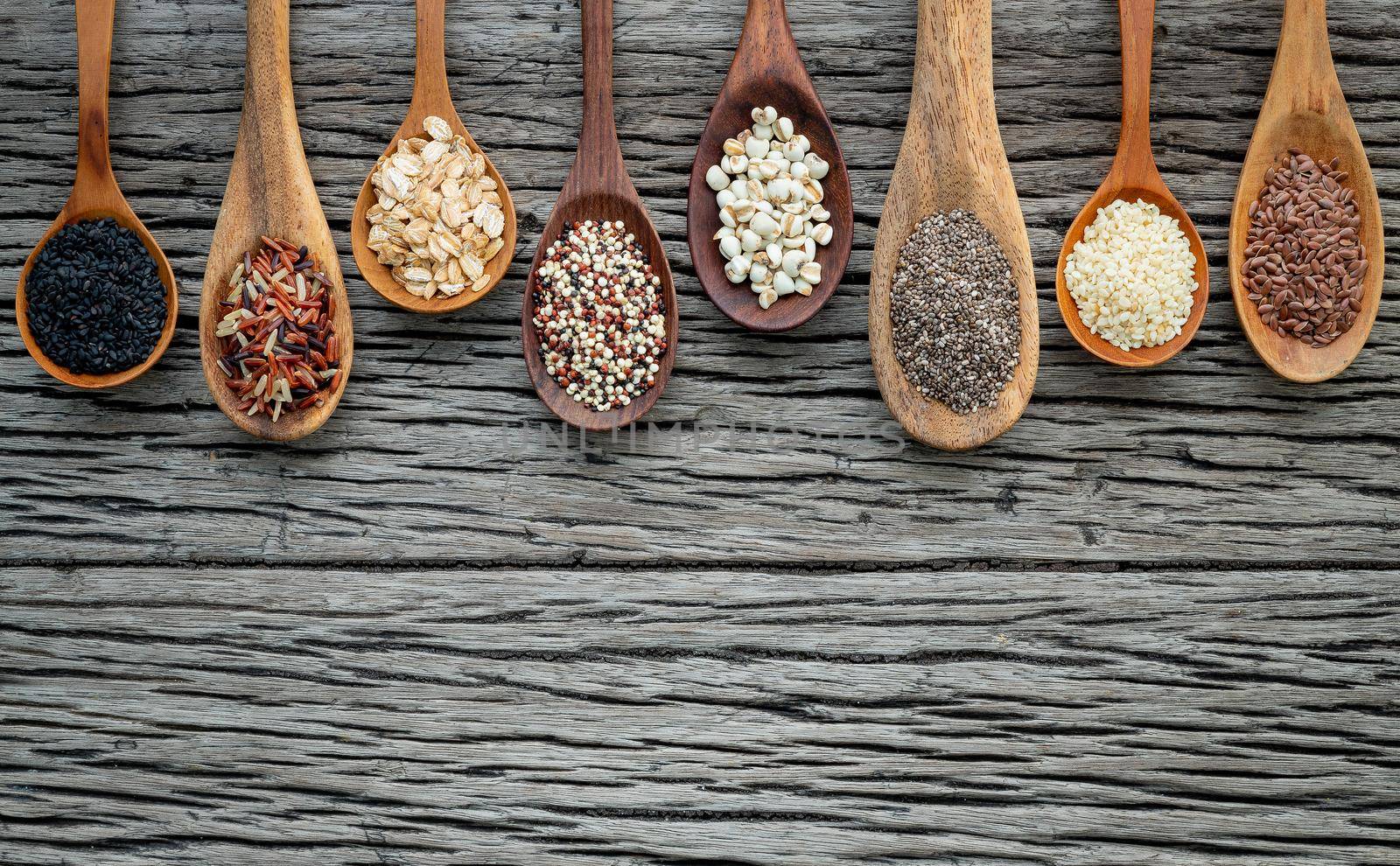 Different types of grains and cereals on shabby wooden background by kerdkanno