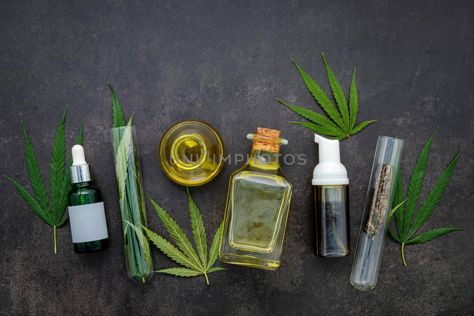 Glass bottle of cannabis oil and hemp leaves set up  on concrete background.  by kerdkanno