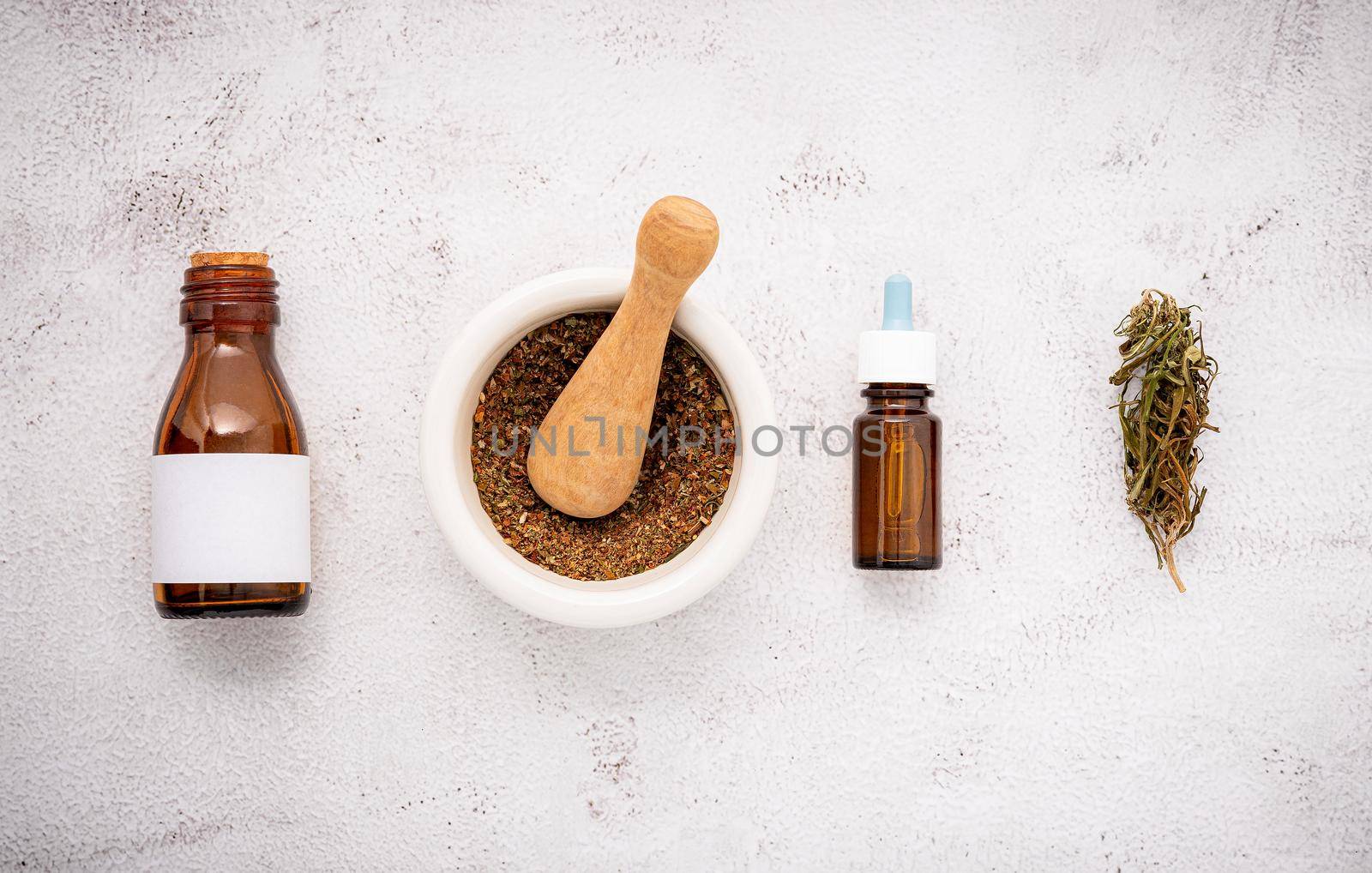 Glass bottle of cannabis oil with white mortar and hemp leaves set up  on concrete background.  by kerdkanno