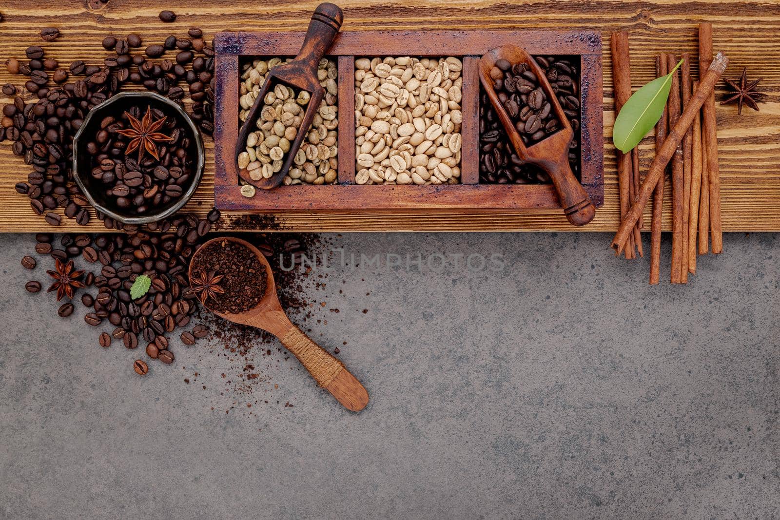 Various of roasted coffee beans in wooden box with manual coffee grinder setup on shabby wooden background. by kerdkanno