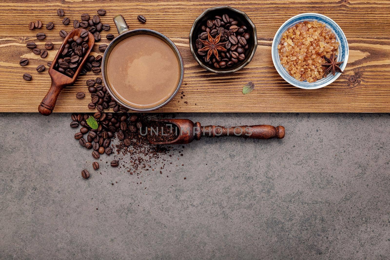 Roasted coffee beans with coffee cup setup on dark stone background.