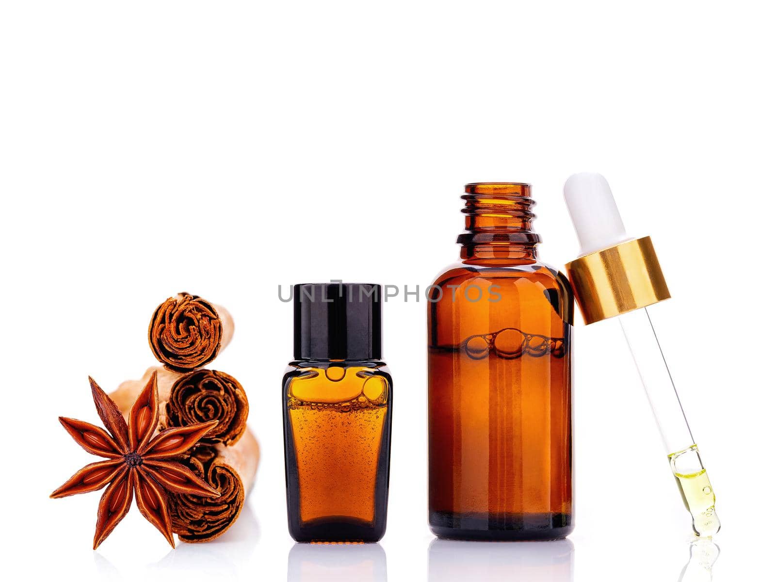 Cinnamon essential oil bottle with Ceylon cinnamon sticks and anise star isolated on white background .