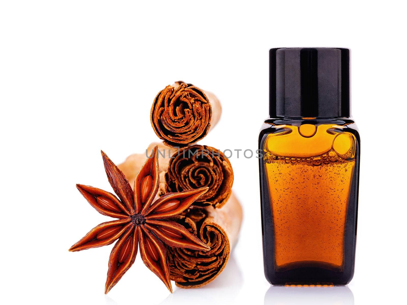 Cinnamon essential oil bottle with Ceylon cinnamon sticks and anise star isolated on white background .
