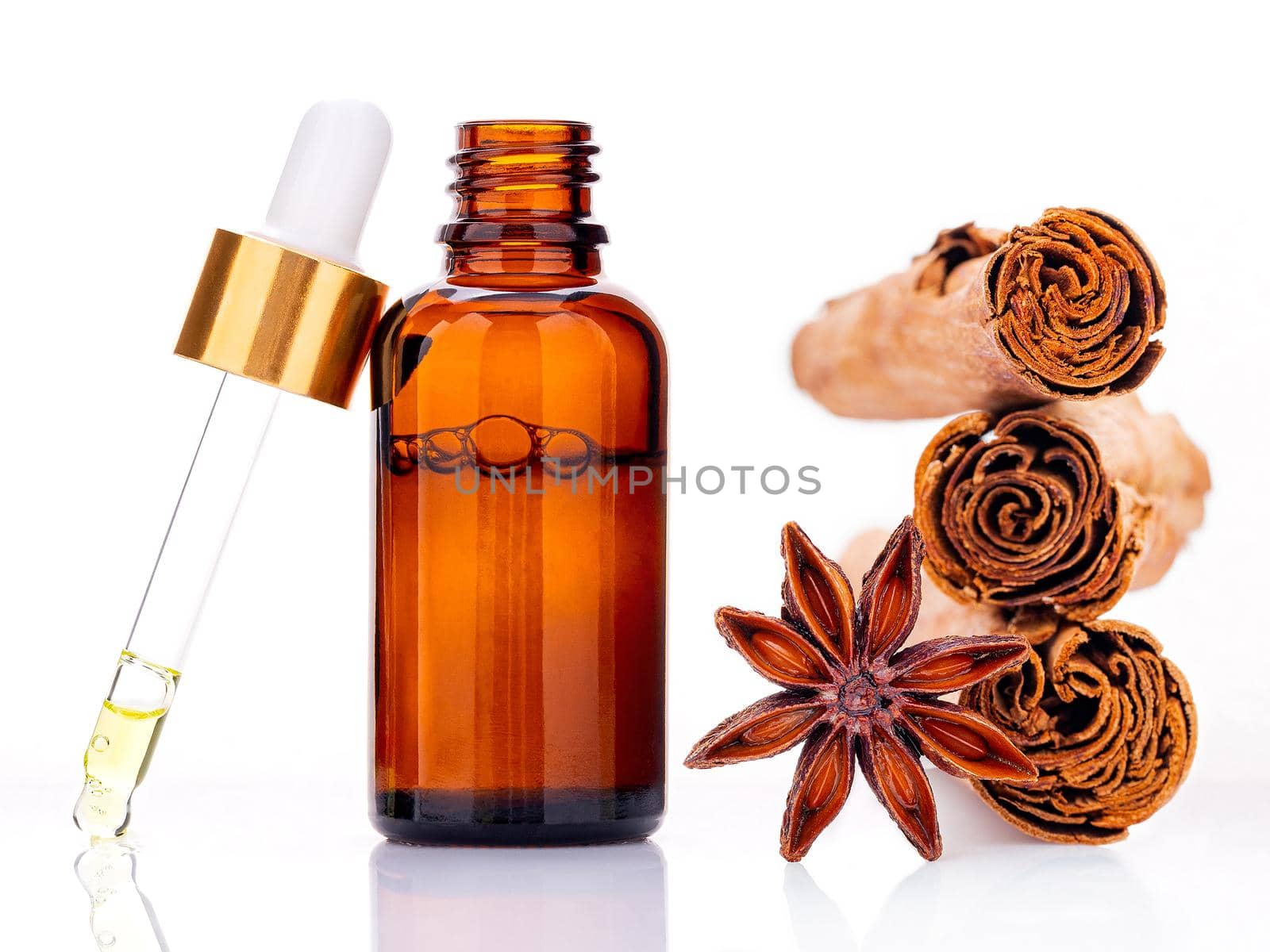 Cinnamon essential oil bottle with Ceylon cinnamon sticks and anise star isolated on white background .