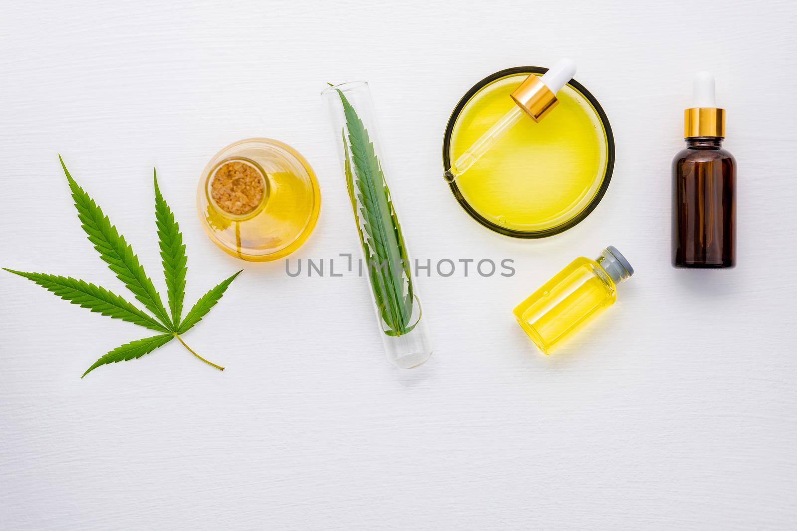 Glass bottle of cannabis oil and hemp leaves set up  on white background.