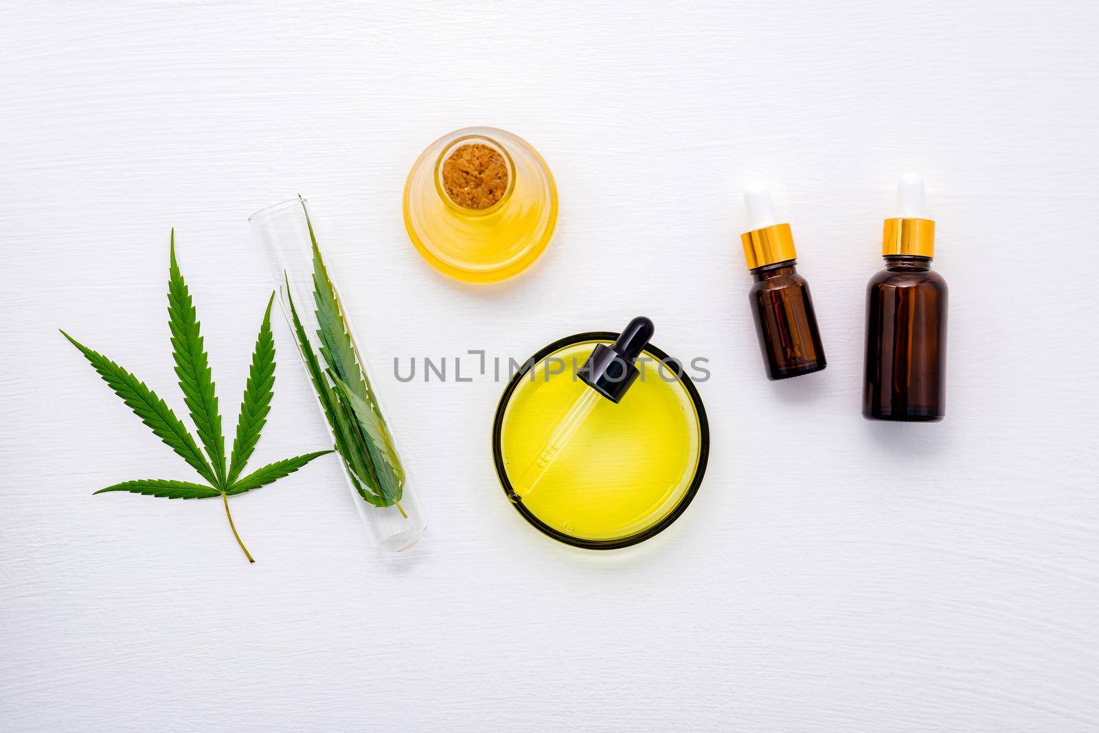 Glass bottle of cannabis oil and hemp leaves set up  on white background.