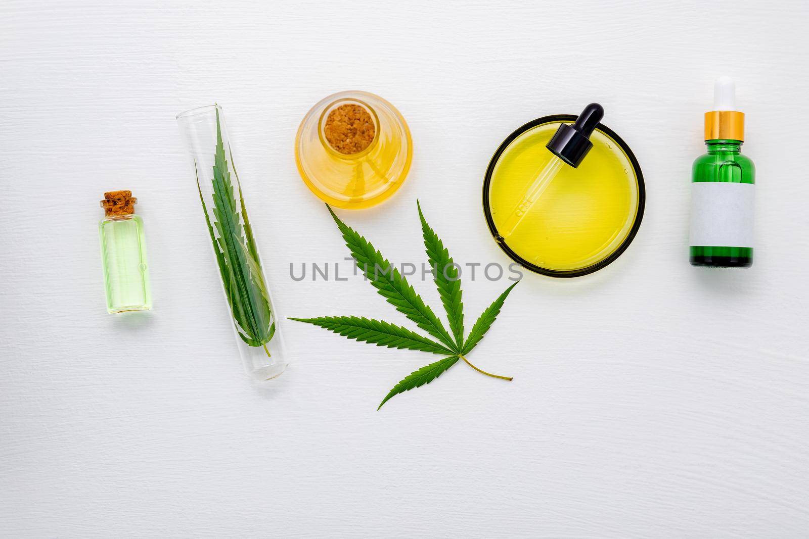 Glass bottle of cannabis oil and hemp leaves set up  on white background.