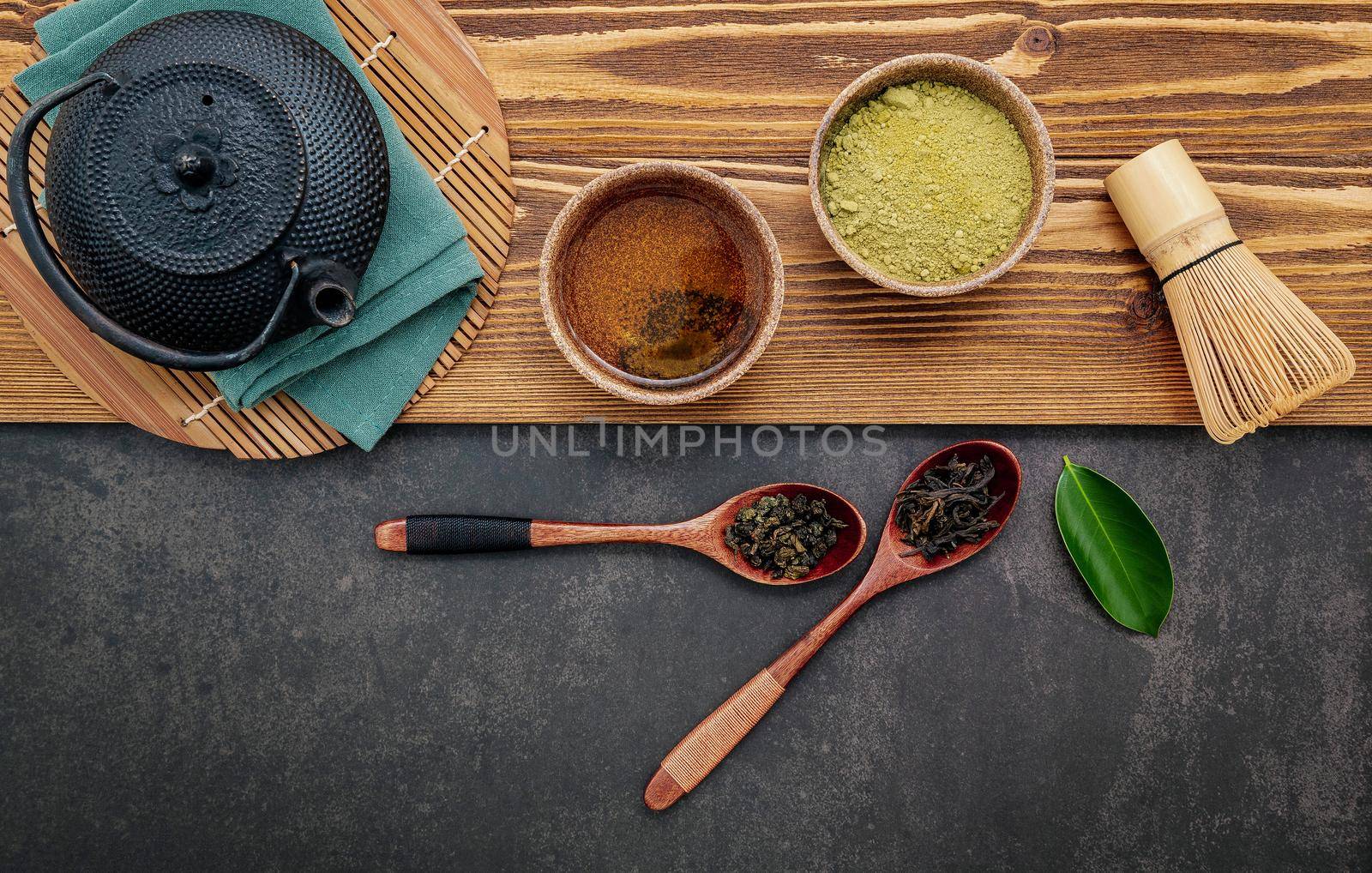 Black cast iron tea pot with herbal tea set up on dark stone background. by kerdkanno