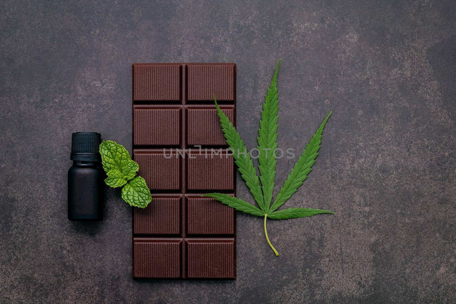 Food conceptual image of  cannabis leaf  with dark chocolate and fork on dark concrete background.