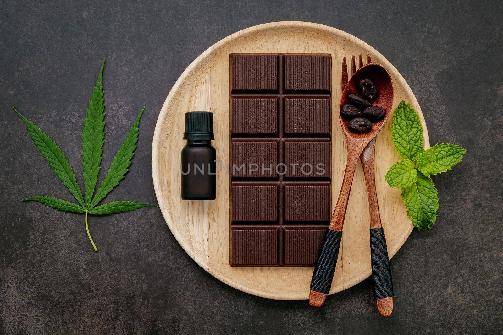 Food conceptual image of  cannabis leaf  with dark chocolate and fork on dark concrete background. by kerdkanno